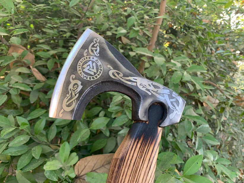 Valknut Viking Axe with engraved design against a green leafy background