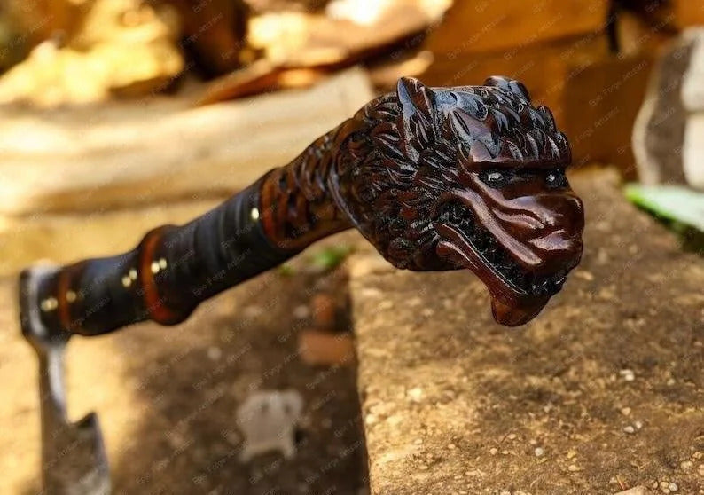 Wooden wolf walking cane with a detailed dragon head handle on a stone surface.