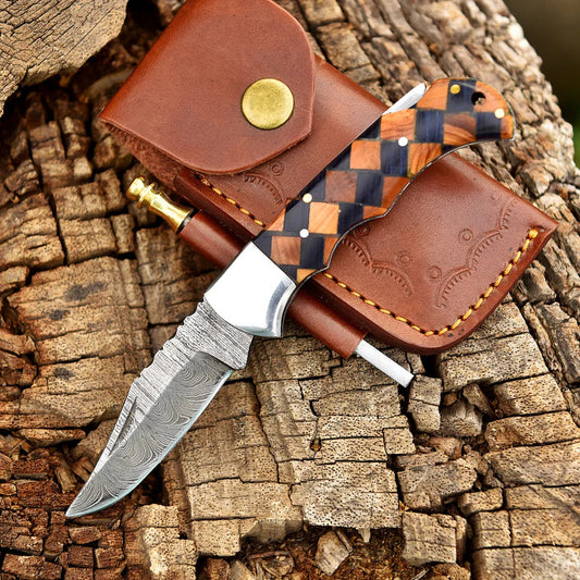 Decorative knife with checkered handle and leather sheath on wooden background