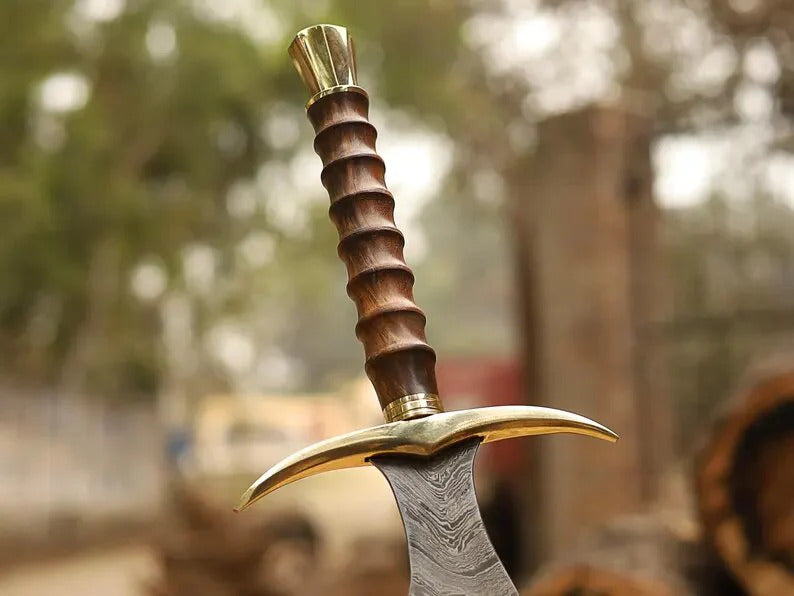Decorative dagger with a wooden handle and gold accents against a blurred natural background