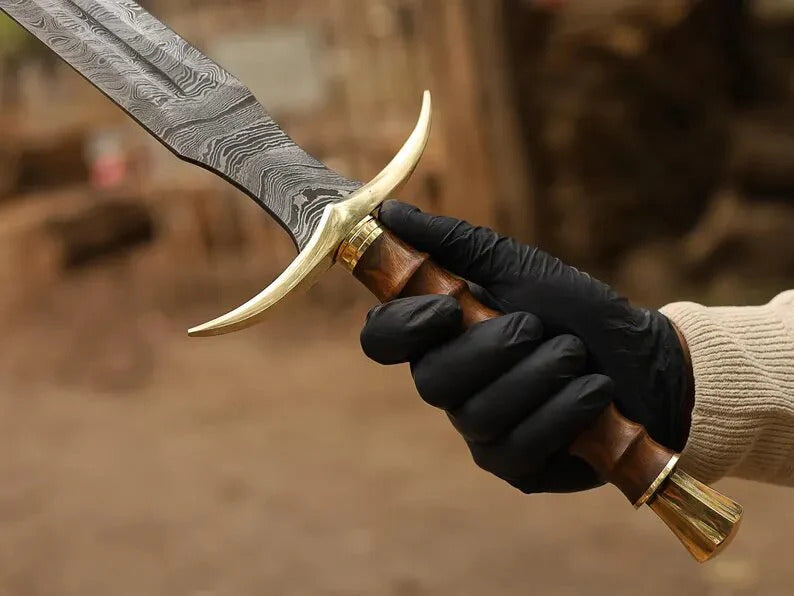 Hand holding a dagger with a decorative handle against a blurred background