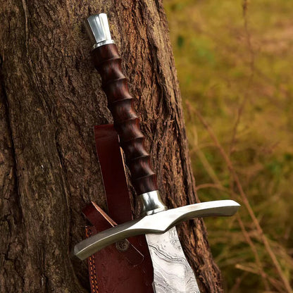 Decorative sword with wooden handle and leather sheath against a tree