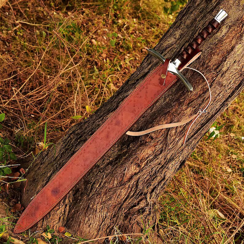 Sword with leather sheath on a tree trunk in a natural setting