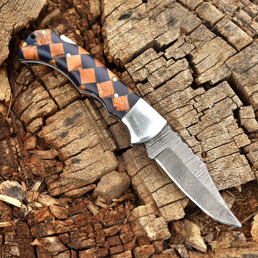 Knife with a checkered handle on a wooden background