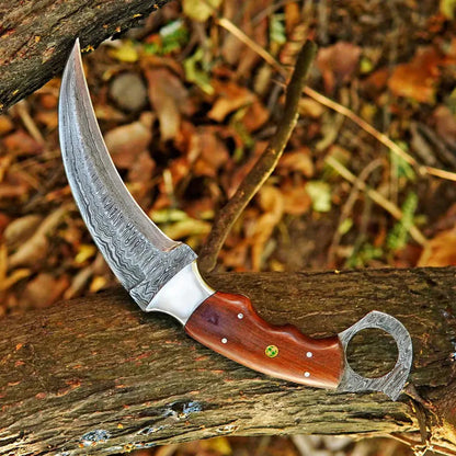 Decorative knife with a wooden handle on a wooden surface with autumn leaves in the background