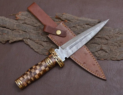 Decorative knife with a checkered handle and leather sheath on a textured surface