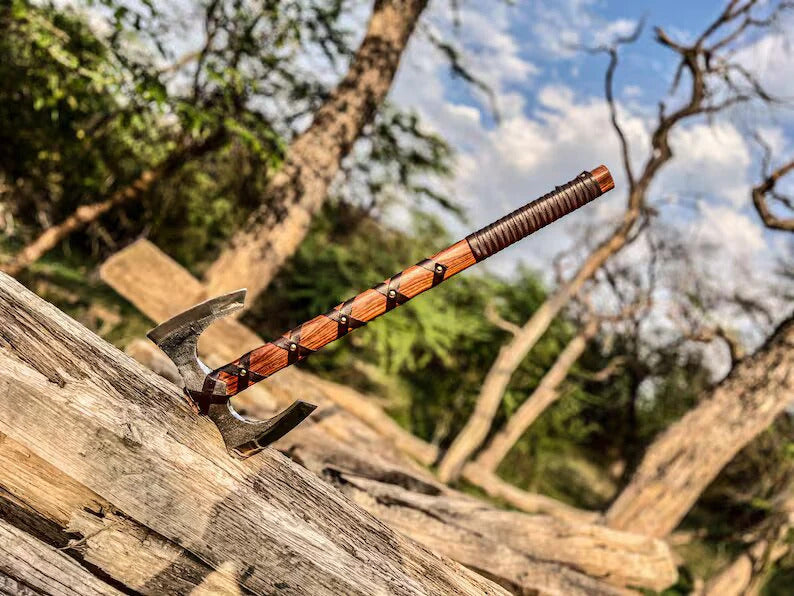 Hatchet with wooden handle on a log against a natural background