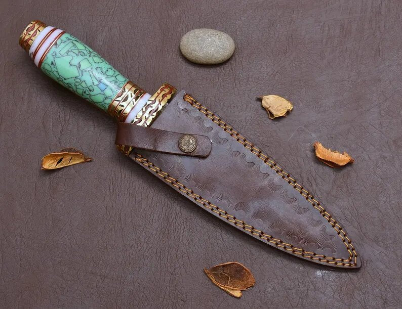 Decorative knife with blue resin handle and brown sheath on a textured surface