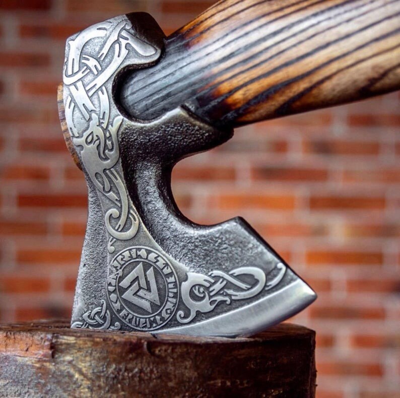 Decorative Hatchet breaded axe with intricate designs on a wooden block against a brick wall background