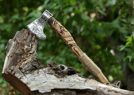 Decorative axe with a wooden handle on a tree stump against a blurred green background