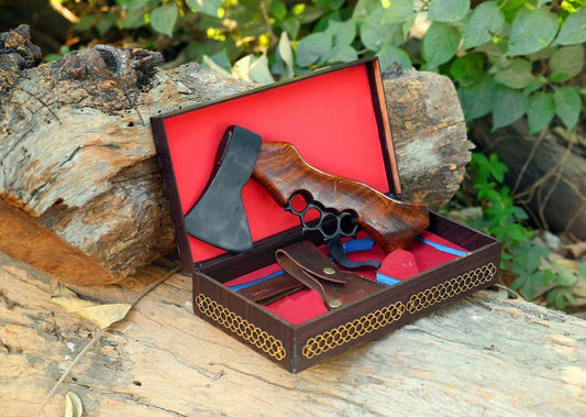 Wooden knuckle duster in a decorative box on a wooden surface with greenery in the background