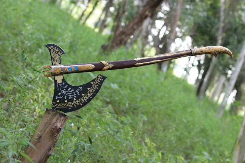 Decorative Kratos Leviathan Viking Axe with intricate designs leaning against a tree in a forest setting