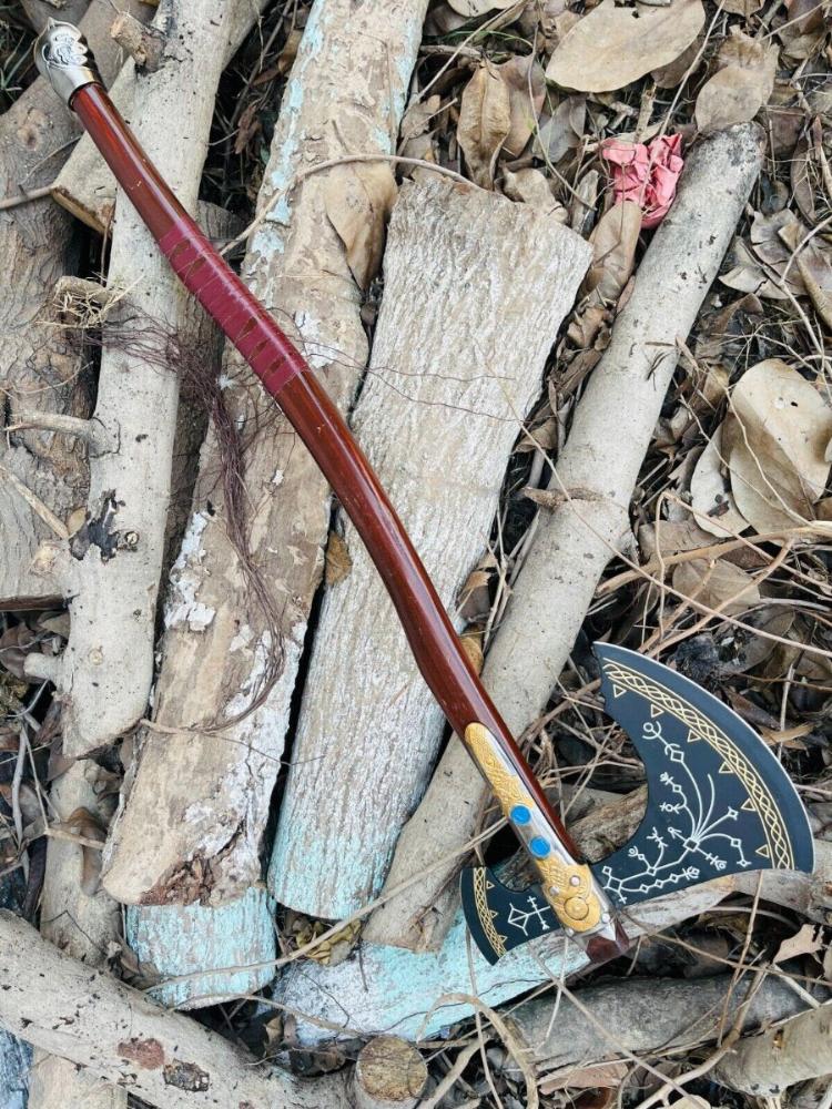 Decorative Kratos Leviathan Viking Axe with a wooden handle and metal blade on a natural background