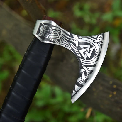 Decorative axe with intricate patterns on a blurred natural background