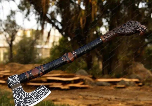 Decorative wolf  axe with a detailed handle against a blurred natural background